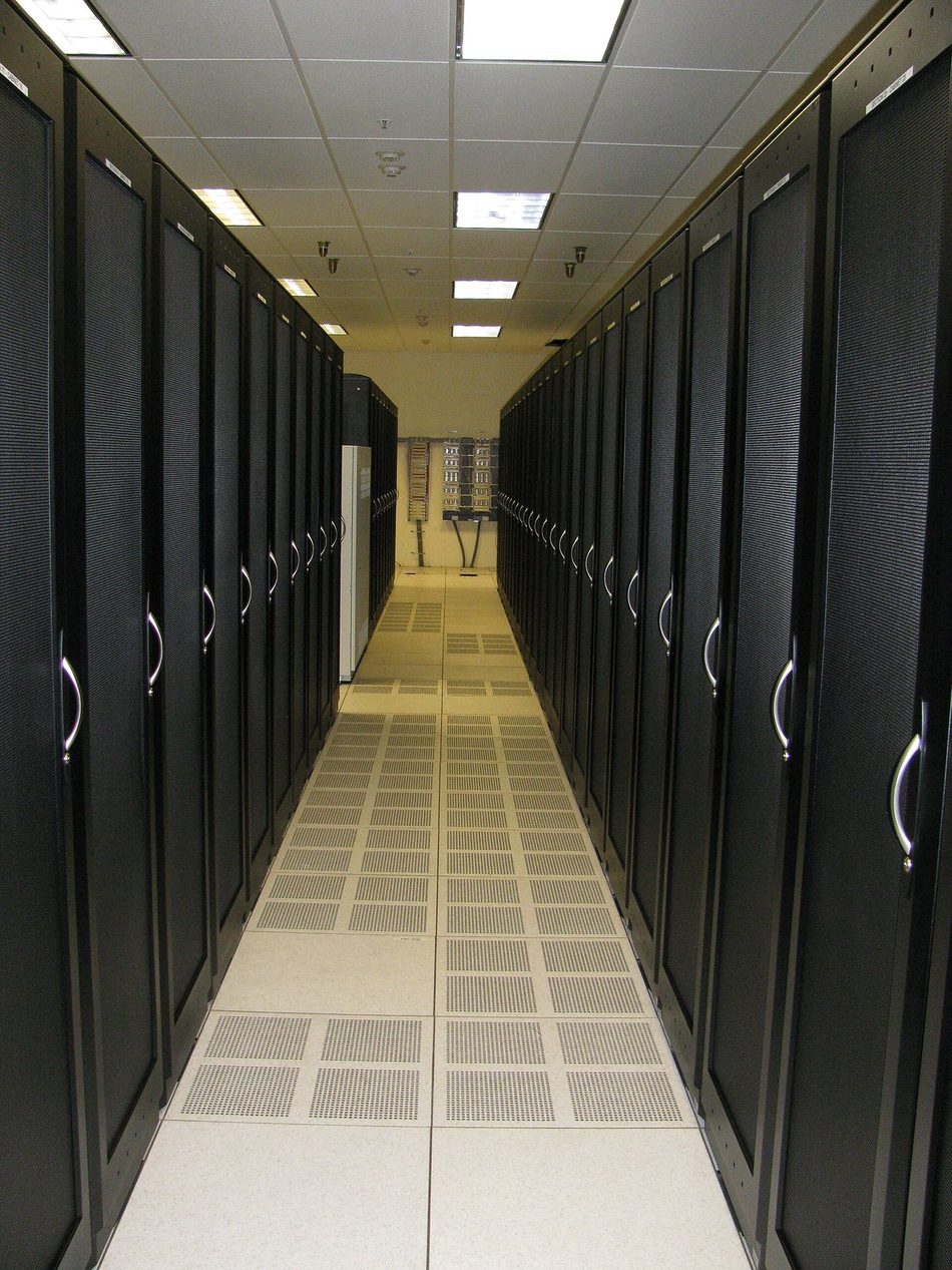 Corredor técnico entre duas fileiras de racks, com piso elevado perfurado